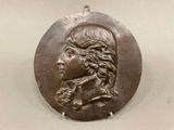 an image of a bronze medallion of a man with long hair