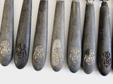 five spoons with silver designs on them on a white surface