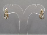 pair of gold and diamond earrings on clear acrylic stand