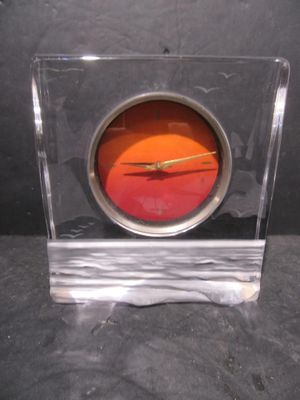 a glass clock with a red face on a black surface