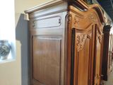 a large wooden armoire in a room with vases on the wall
