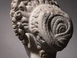 a white marble head of a woman with curly hair