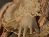 a close up of a doll wearing a dress and holding a book