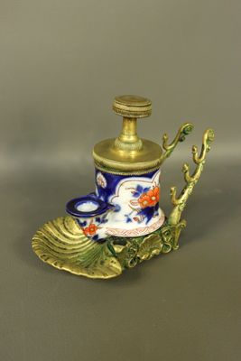 a small blue and gold vase with a leaf on it