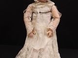 an old fashioned doll with a white dress and bonnet on a black background