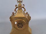 a gold clock sitting on a table with a white background