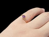 someone is holding a ring with a purple stone on it