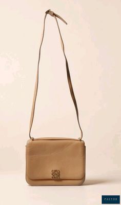 un sac à main beige posé sur une table près d'un mur blanc