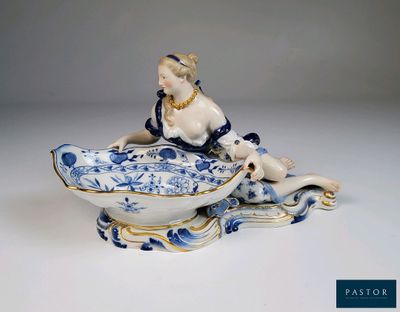 une figurine ancienne en porcelaine représentant une femme assise à l'avant d'un bateau
