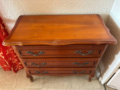 une petite commode en bois dans un coin de la pièce