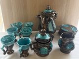 many pieces of pottery on a table with a white table cloth