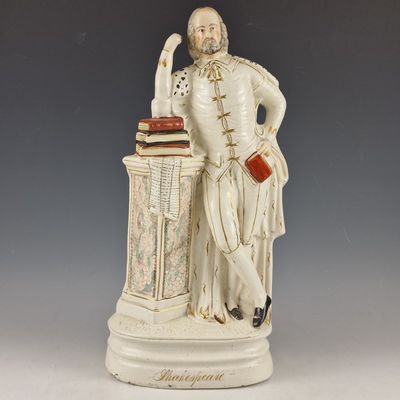 statue représentant un homme assis à un bureau sur lequel se trouve un livre