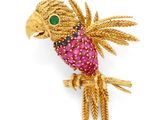 un gros plan sur une broche en forme d'oiseau en or, ornée de pierres roses et vertes