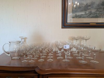 a lot of wine glasses on a table with a picture on the wall in the background
