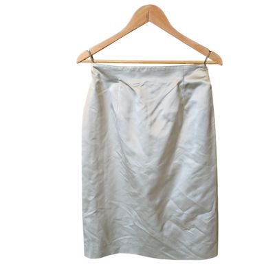 a white skirt hanging on a wooden hanger on a white wall