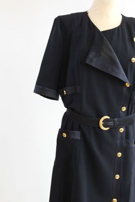 une photo d'une robe noire ornée de boutons dorés