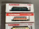 trois trains miniatures sont empilés les uns sur les autres sur une table