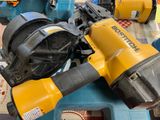 a yellow and black cordless nailer and a blue and yellow cordless nailer on a table