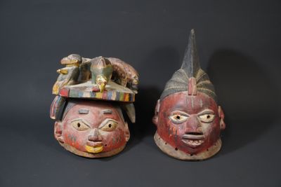 two wooden masks with faces on them sitting next to each other