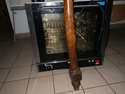 un four dont la porte est ouverte et d'où sort un bâton en bois