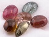 several different colored stones are arranged in a row on a white surface