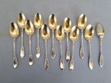 six cuillères en argent sont alignées sur une surface grise