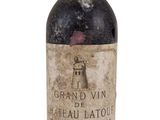 an old bottle of wine sitting on top of a white surface