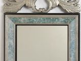 a mirror hanging on the wall with a bird on it