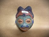 a ceramic mask on a leather surface with a tag on it