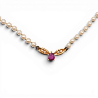 a close up of a necklace with pearls and a pink stone