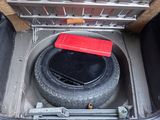 a tire in the trunk of a car with a red lid