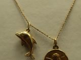 two gold necklaces with a dolphin and a coin on a mannequin