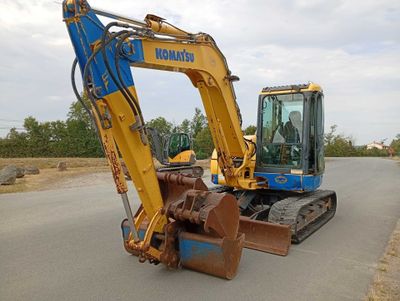 une pelleteuse jaune et bleue garée sur le bord de la route