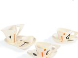 three white cups and saucers with black and orange designs on them