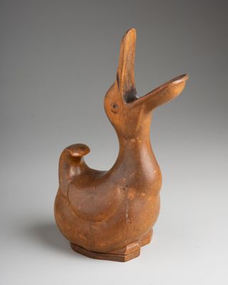 a brown bird shaped vase sitting on top of a table