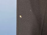 a close up of a black suit with a small yellow spot on the lapel