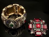 une paire de bracelets rouges et verts et une bague posés sur un fond noir