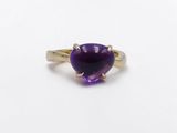 a close up of a purple stone ring on a white surface