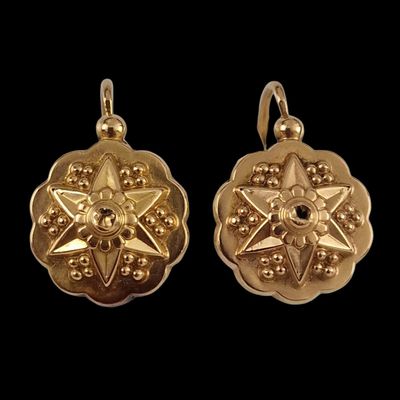 a pair of gold earrings with a star design on them