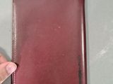 someone is holding a brown leather wallet on a table
