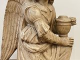 statue of an angel holding a bowl of food on a black mat