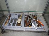 de nombreux types de couteaux et de cuillères exposés dans une vitrine