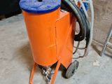 une machine orange sur laquelle est posé un seau bleu, dans une pièce
