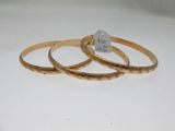 three gold bang bracelets on a white surface with a price tag
