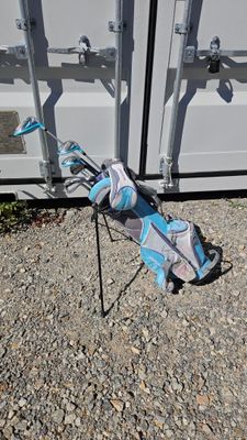 a bag of golf equipment on the ground next to a container