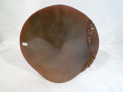 une assiette marron posée sur une surface blanche