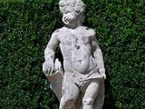a statue of a boy holding a bird in a garden