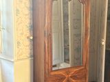a wooden cabinet with a glass door in the corner of a room