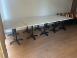 des tables et des chaises dans une pièce avec un parquet et un mur blanc