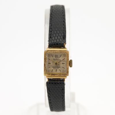 une photo d'une montre en or avec un bracelet en cuir noir